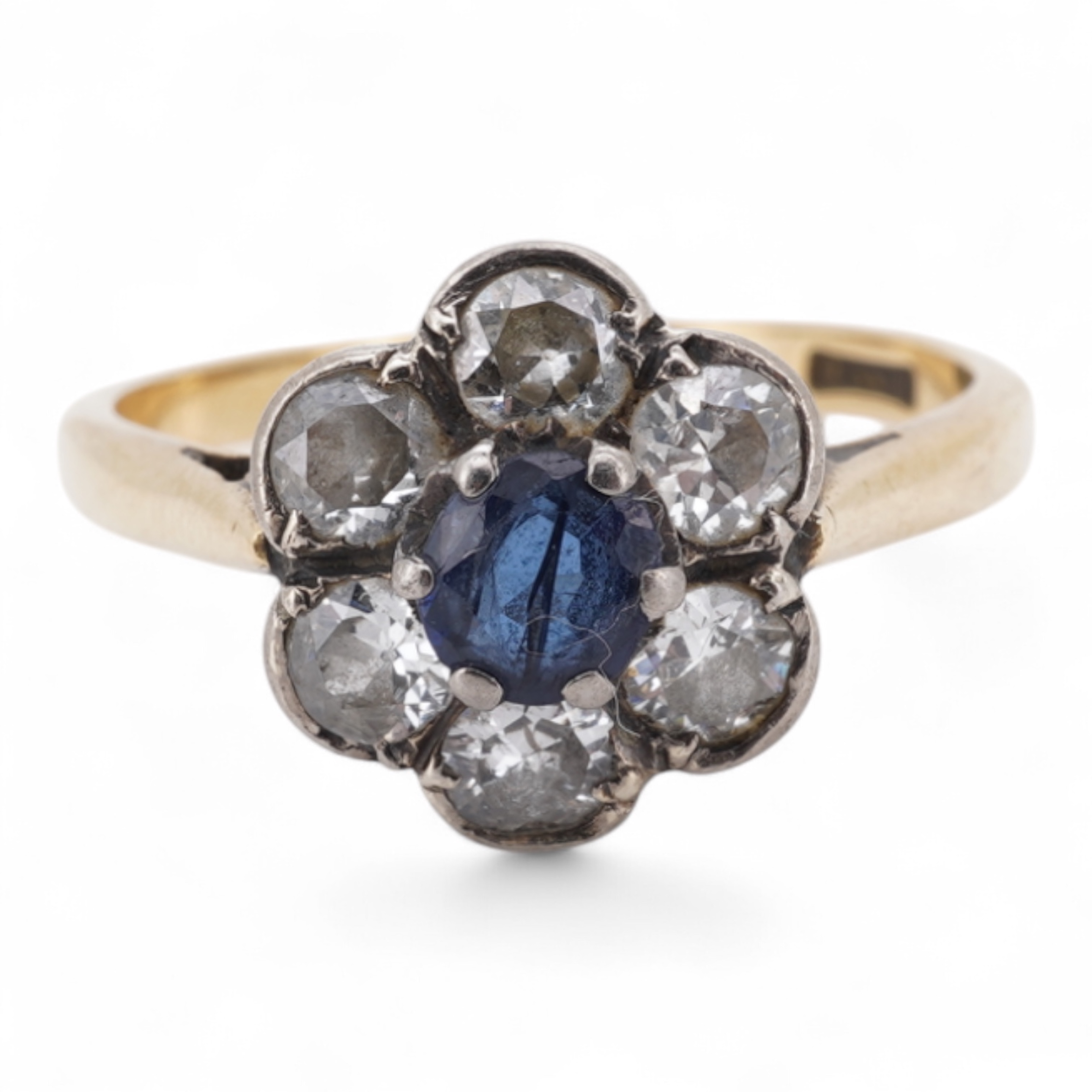 An early to mid 20th century yellow metal (stamped 18ct), singe stone sapphire and six stone diamond set circular cluster ring, size O, gross weight 3.7 grams.